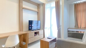 Ein modernes Wohnzimmer mit Flachbildfernseher, Holzmöbeln, einer Couch und einem Esstisch.