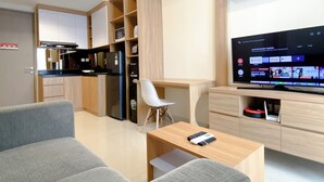 Ein modernes Wohnzimmer mit einer Couch, einem Couchtisch, einem Fernseher, der eine Systemaktualisierung für Android anzeigt, und einer Küchenzeile mit Holzausstattung und Geräten.