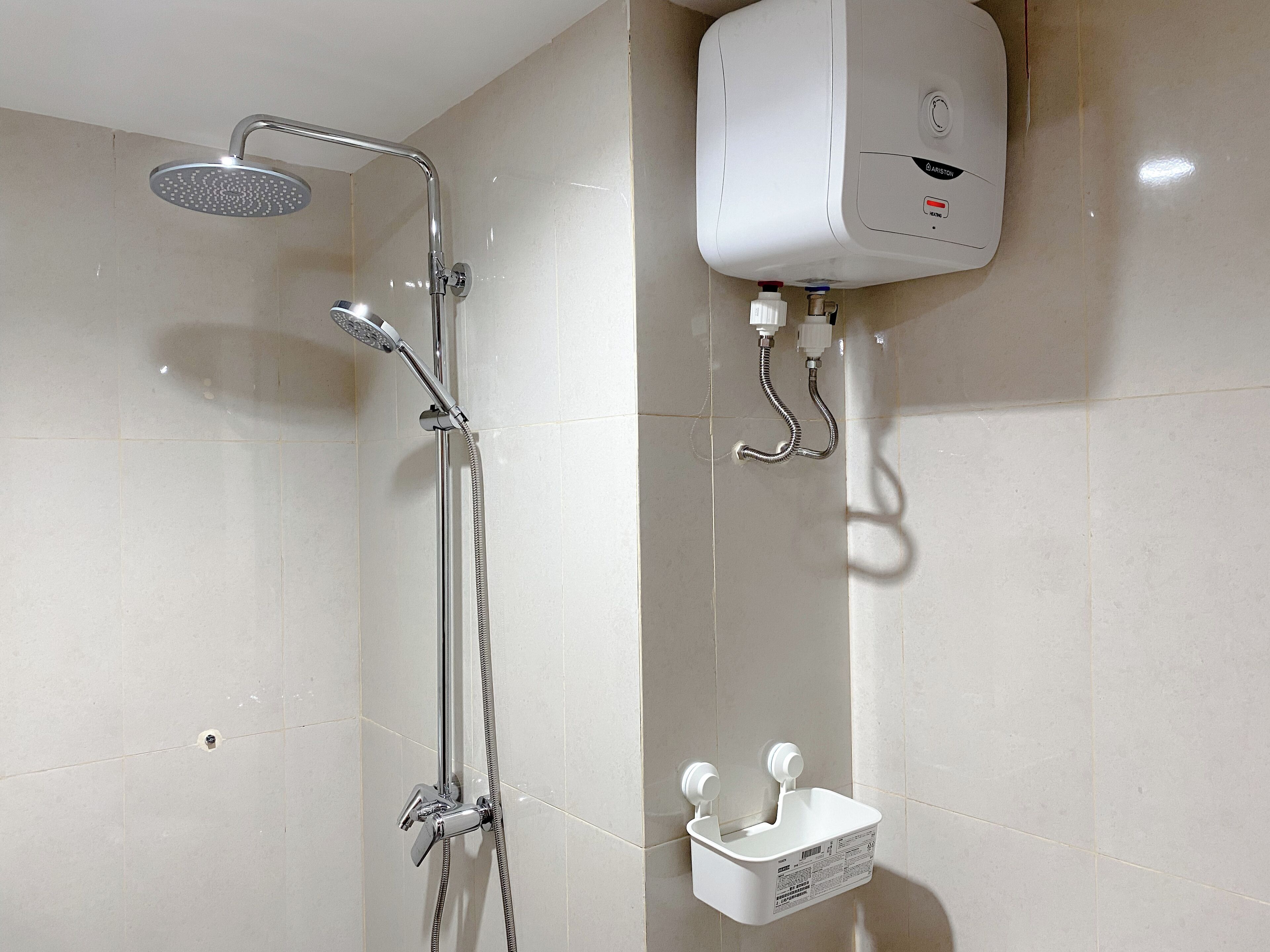 A modern bathroom with a shower, a wall-mounted water heater, and a soap dispenser.