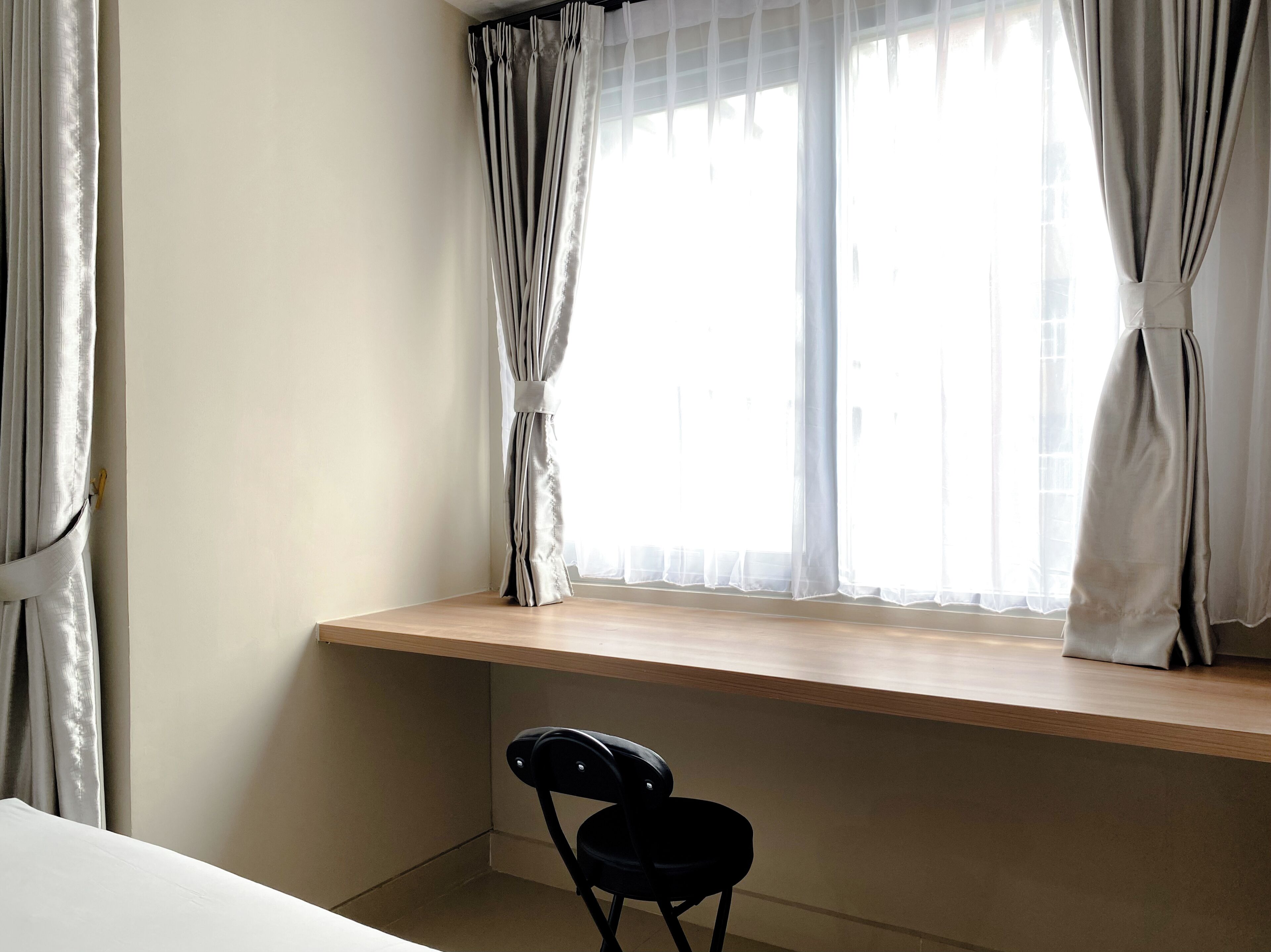 A room with a wooden desk, a chair, and a window with curtains.