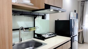 Eine moderne Küche mit Spülbecken aus Edelstahl, einem Gasherd und einem schwarzen Kühlschrank.