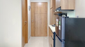 Eine schmale Küche mit Holzschränken, einem Edelstahlkühlschrank und einer weißen Arbeitsplatte.