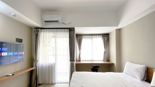 Ein Hotelzimmer mit Bett, Wandfernseher, Klimaanlage und einem fenster mit Vorhängen.