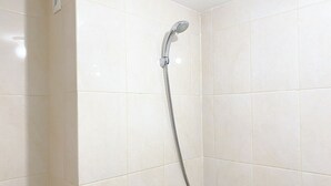 A shower with a handheld showerhead and a wall-mounted faucet.