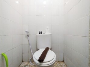 Bathroom features a toilet, shower hose, and storage for essentials.