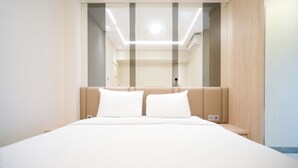 Une chambre d’hôtel moderne avec un grand lit, une armoire intégrée et un grand miroir.