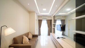 Une chambre d’hôtel moderne équipée d’un canapé, d’un miroir, d’un téléviseur à écran plat et d’une lampe.