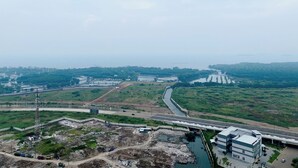 Luchtbeeld van een kustgebied met een rivier, een brug en een groot gebouw met een modern ontwerp.