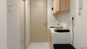 Een smalle keuken met witte kastjes, een spoelbak en een zwart aanrecht.