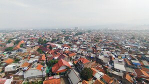 A densely packed urban area with numerous buildings, some with red-tiled roofs, and a hazy sky. - Nice And Comfortable Stay Studio At Gateway Ahmad Yani Cicadas Apartment (Bandung)