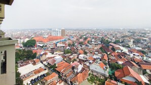 A cityscape with a mix of residential and commercial buildings, including a prominent white building with a blue roof and a tall structure in the distance. - Nice And Comfortable Stay Studio At Gateway Ahmad Yani Cicadas Apartment (Bandung)