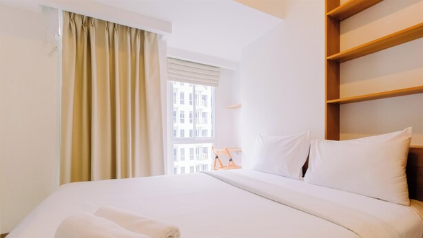 Une chambre d’hôtel avec un lit bien fait, une fenêtre avec des rideaux et une étagère en bois.