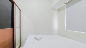 A hotel room with a bed, a wooden wardrobe, and a window. - Modern Look 2Br At Serpong Greenview Apartment (South Tangerang)