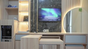 Ein modernes Hotelzimmer mit Schreibtisch aus Holz, einem Flachbildfernseher, der das Nordlicht zeigt, einem eingebauten Backofen und einem großen Spiegel.