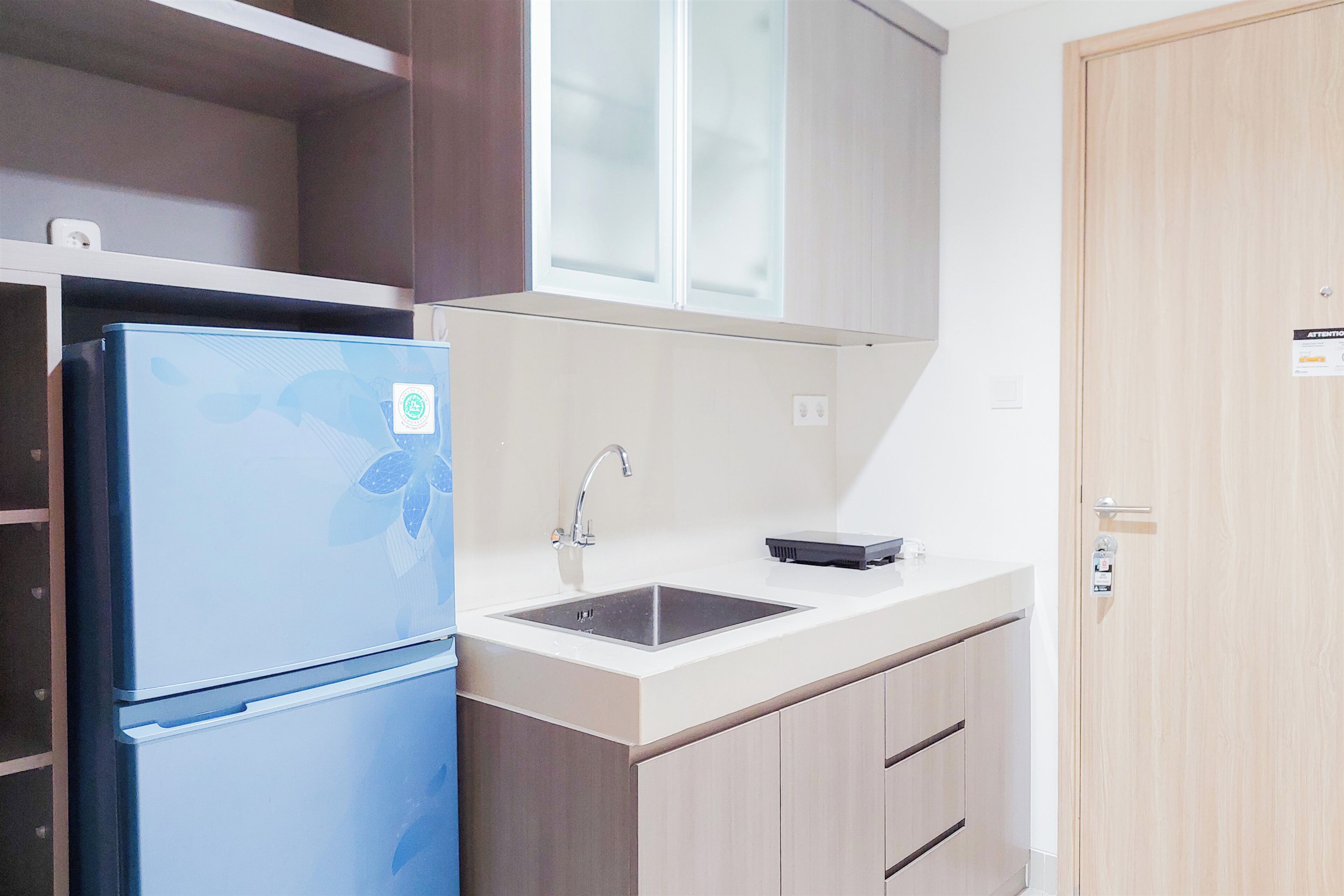 Een kleine keuken met een blauwe koelkast, een spoelbak en houten keukenkastjes.