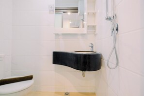 A bathroom with a white toilet, a black sink, and a shower. - Strategic Studio Apartment Sky House Bsd Near Aeon Mall (Pagedangan)