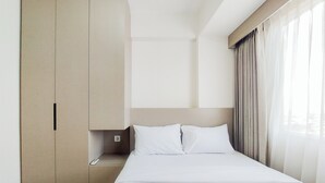 Ein Hotelzimmer mit Bett, Schrank und einem fenster mit Vorhängen.