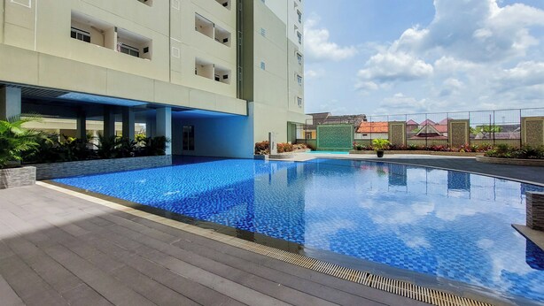 Ein modernes Hotel mit Schwimmbad, einem überdachten Gang und Blick auf die umliegenden Gebäude.