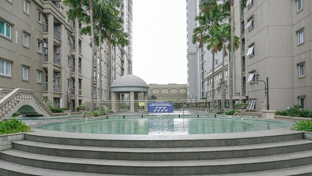 Piscina rodeada por um edifício residencial com vários andares e uma estrutura em forma de cúpula no centro.