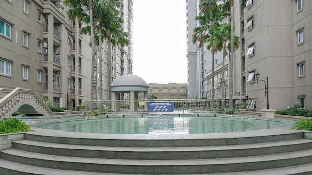 A swimming pool surrounded by a multi-story residential building with a dome structure in the center.