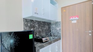 A kitchen with a marble countertop, a gas stove, a sink, and white cabinets. - Homey And Restful Studio Royal Sentul Park Apartment (Bogor)