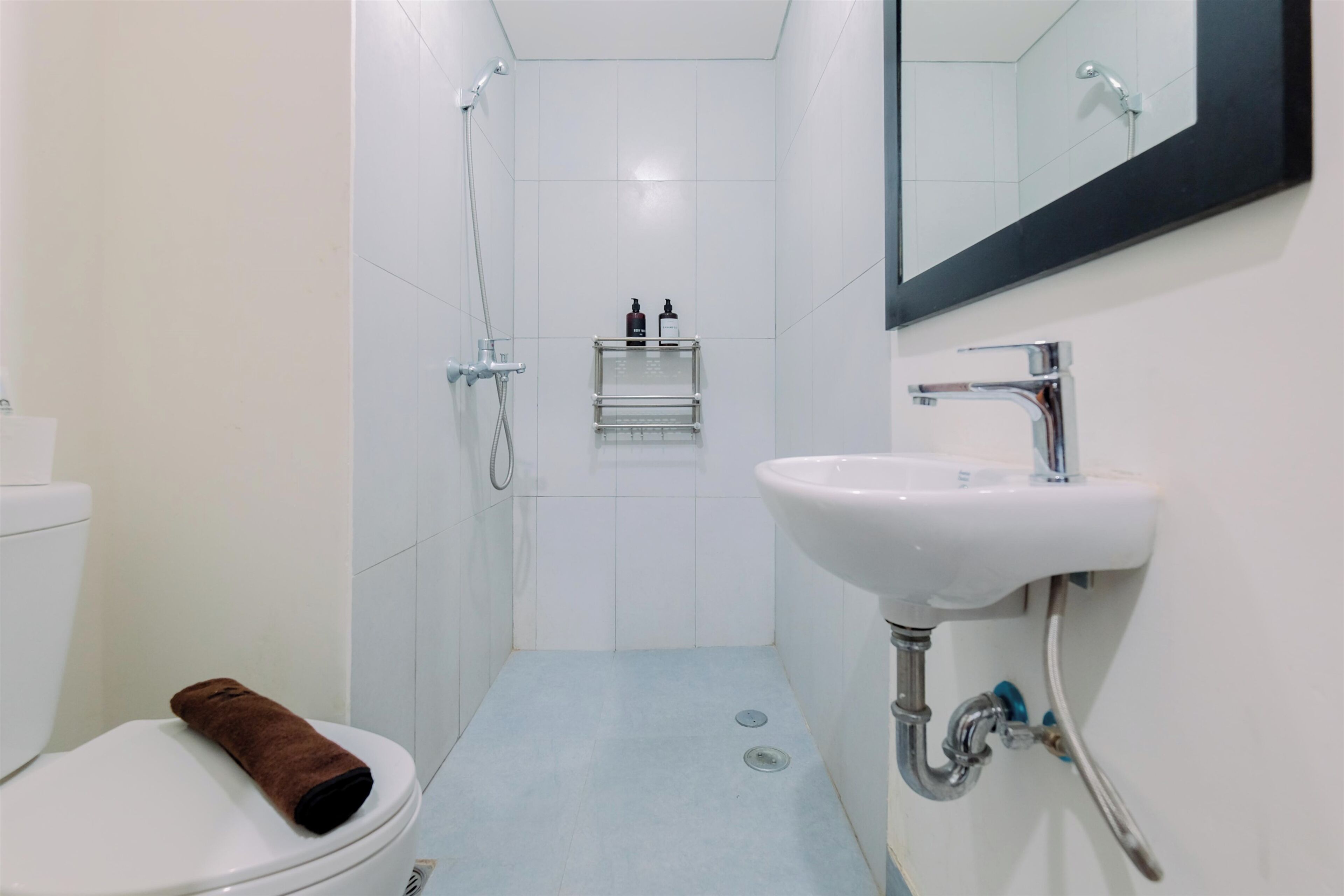 A small, modern bathroom with a toilet, a sink, a shower, and a mirror.