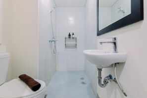 Ein kleines, modernes Badezimmer mit Toilette, Waschbecken, Dusche und Spiegel.