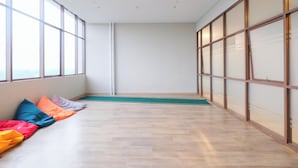A room with large windows, a wooden floor, and a green mat. - Cozy And Restful Studio Lrt City Sentul - Royal Sentul Park Apartment (Bogor)
