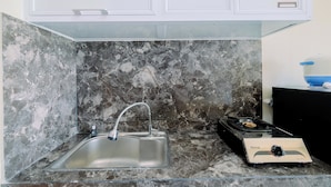 A kitchen with a stainless steel sink, a gas stove, and marble walls. - Cozy And Restful Studio Lrt City Sentul - Royal Sentul Park Apartment (Bogor)