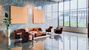 A modern lobby with a polished floor, a sofa, chairs, and two large woven wall art pieces. - Comfy And Modern Studio Room The Ayoma Apartment (South Tangerang)