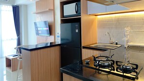 Eine moderne Küche mit Holzschränken, einem schwarzen Kühlschrank, einer Mikrowelle, einem Gasherd und einem eingebauten Backofen.