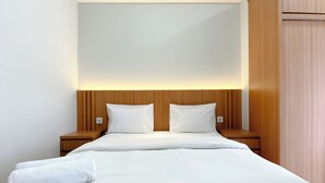 Ein Hotelzimmer mit einem ordentlich bezogenen Bett, einem Holzkopfteil und Nachttischen.