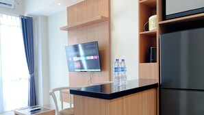 Eine moderne Küche mit einem eingebauten Kühlschrank, einem flachbildfernseher an der Wand und einer Holzeinsel mit Glasplatte.