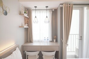 Een hotelkamer met een bed, een bureau met twee stoelen, een raam met gordijnen en twee hanglampen.