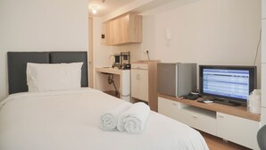 Ein Hotelzimmer mit Bett, Schreibtisch mit Computer und einer Küchenzeile.