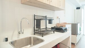 Eine Küche mit Spüle aus Edelstahl, Holzschränken, einem schwarzen Drahtgestell und einem Küchengerät auf der Arbeitsfläche.