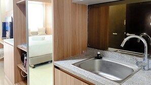 A modern kitchen with a granite countertop, stainless steel sink, and wooden cabinetry. - Simply Look Studio At Mustika Golf Residence (No Kitchen) Apartment (Cikarang)