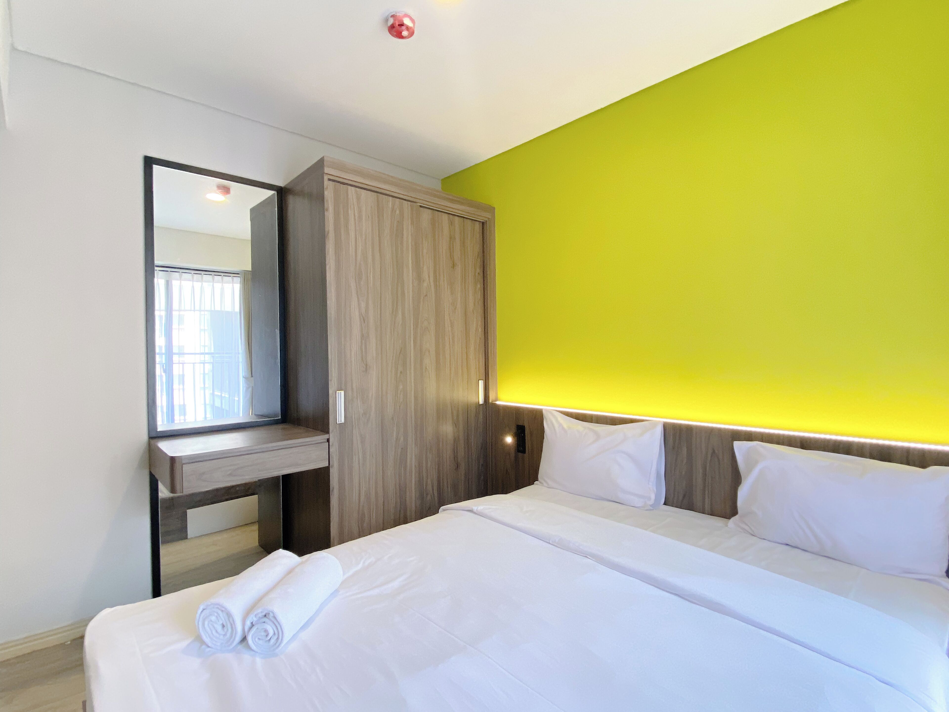 Een hotelkamer met een bed, een spiegel, een kledingkast en een felgroene accentmuur.