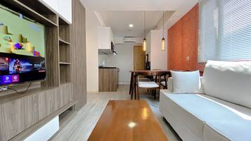 A modern living room with a wooden coffee table, a white sofa, and a TV mounted on a wooden panel wall.