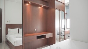A modern bedroom with a wooden wardrobe, a bed with white linens, a desk with a chair, and a large mirror. - Good Deal And Comfort Stay 2Br Transpark Cibubur Apartment (Depok)
