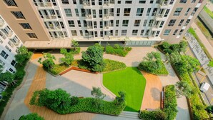 An aerial view of a residential building complex with multiple balconies, a central green lawn, and surrounding landscaped areas. - Simply Look And Cozy Studio Tokyo Riverside Pik 2 Apartment (Teluknaga)