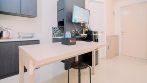Eine moderne Küche mit Flachbildfernseher, Kaffeemaschine und einem Schreibtisch für Reisende.