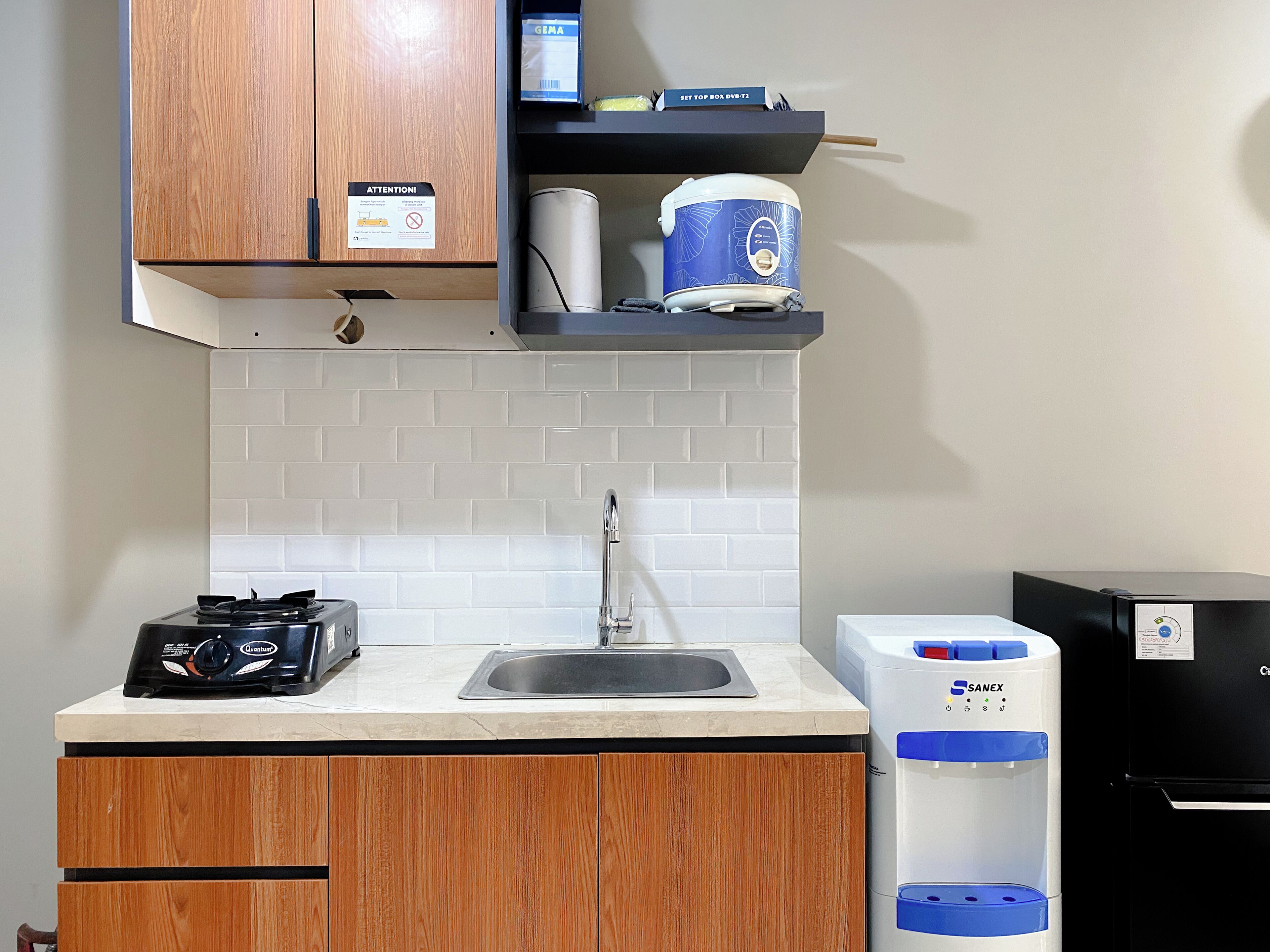 A kitchen with a gas stove, a sink, a water dispenser, and wooden cabinets.