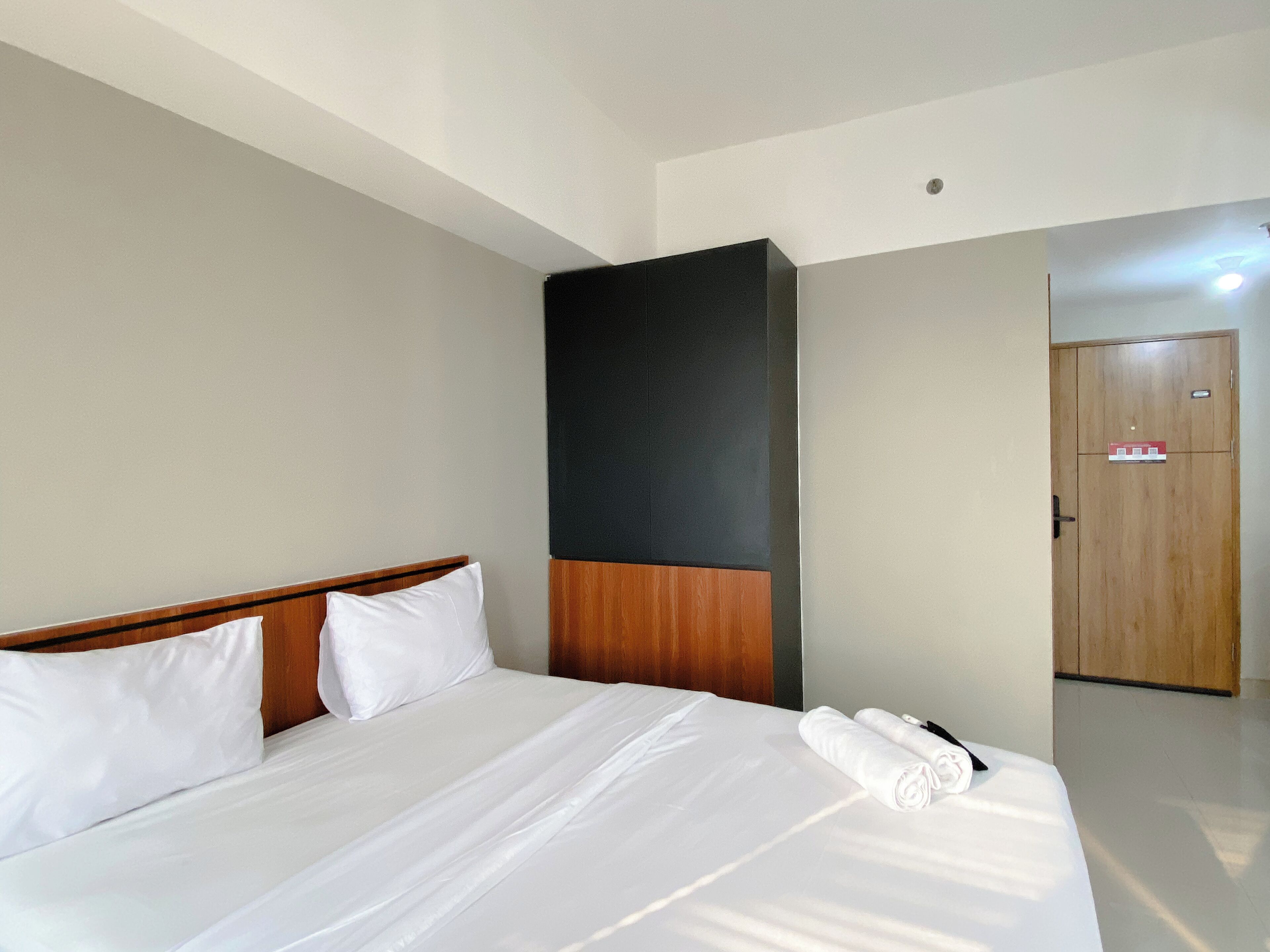 A hotel room with a large bed, wooden headboard, and a door with a sign.