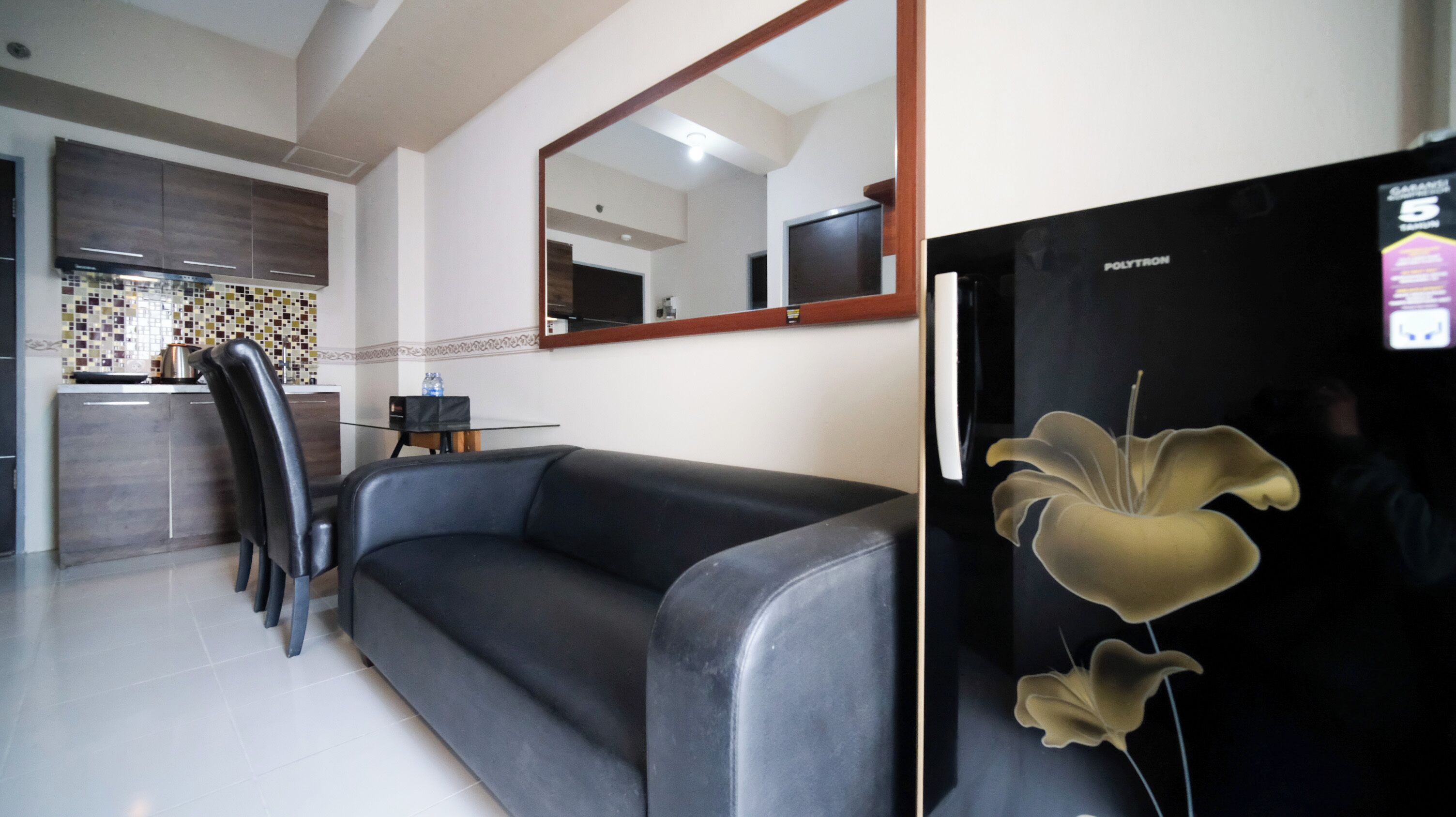 A modern kitchen with dark cabinets, a black refrigerator, and a glass-top dining table.
