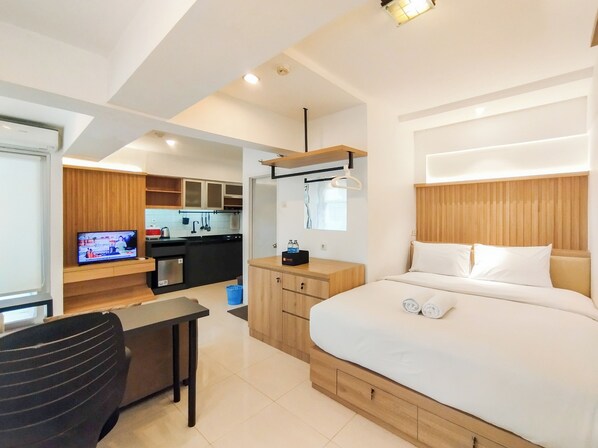 Une chambre d’hôtel moderne équipée d’un lit, d’un bureau, d’une télévision et d’un coin cuisine.
