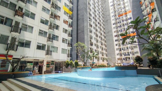 A multi-story residential building with balconies, a swimming pool, and a small garden area. - Spacious Classic Studio At Jarrdin Cihampelas Apartment (Bandung)