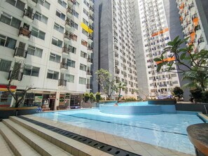 A multi-story residential building with balconies, a swimming pool, and a small garden area. - Spacious Classic Studio At Jarrdin Cihampelas Apartment (Bandung)