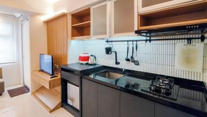 A modern kitchen with a black countertop, white tiled backsplash, and a built-in stove. - Spacious Classic Studio At Jarrdin Cihampelas Apartment (Bandung)