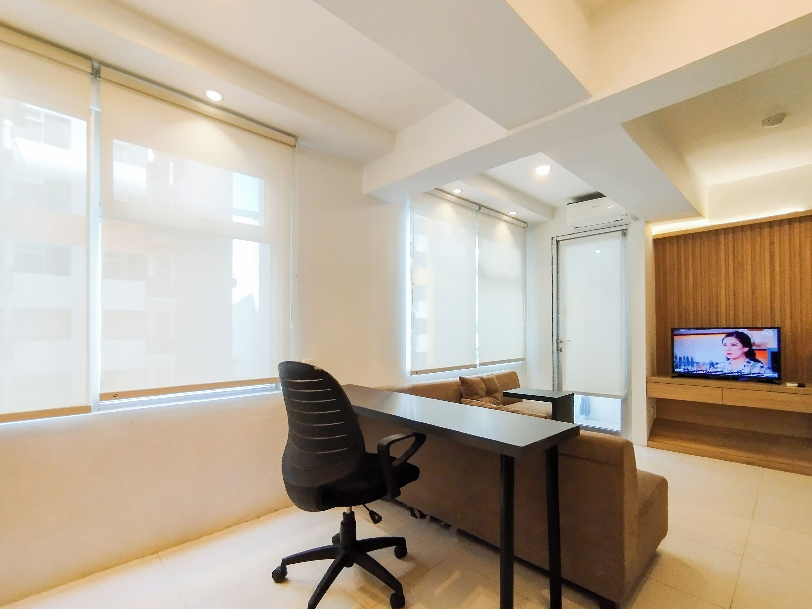 A modern office space with a desk, office chair, sofa, and a television.